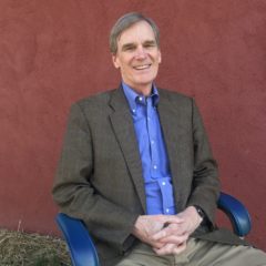 Man in jacket sitting in chair.