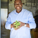 Man standing holding okra in his hands.