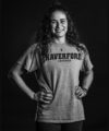 Curly haired girl standing with hands on her hips wearing a gray Haverford Lacrosse t-shirt