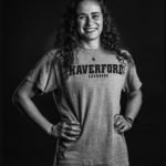 Curly haired girl standing with hands on her hips wearing a gray Haverford Lacrosse t-shirt