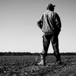 A black and white photo of Edmund Clark standing in a field in the Mississippi Delta