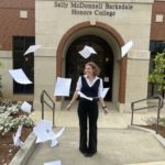 Mattie Ford smiles as she throws the pages of her thesis in the air outside of the Honors College.