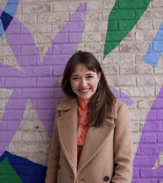 Sarah Morgan poses against a colorful brick wall